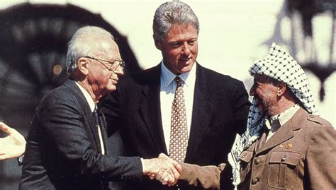 Le président américain Bill Clinton étend les bras derrière le Premier ministre israélien Yitzhak Rabin et le leader de l'autorité palestinienne Yasser Arafat, le 13 septembre 1993, à Washington, lors la signature des accords d'Oslo.